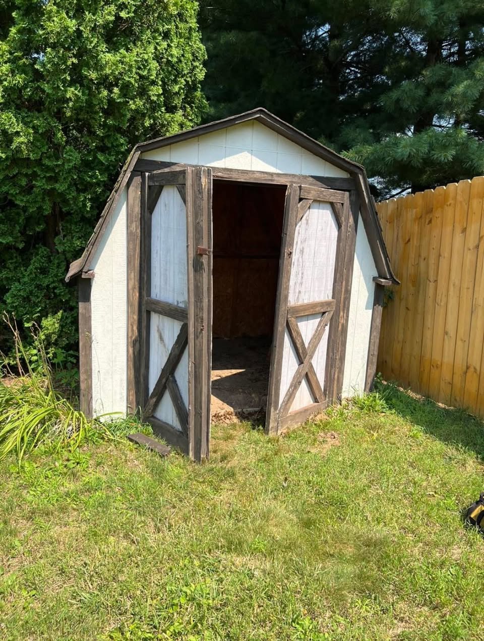 Weathered backyard storage shed beside a fence