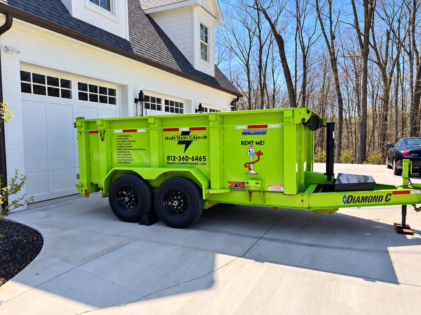 Sears Trash Cleanup’s bright green dump trailer parked beside a Bloomington home
